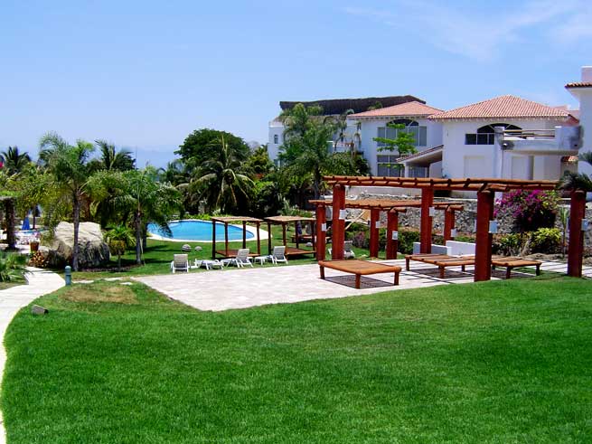 Pergolas and lounge chairs surrounded by manicured gardens, beachfront ¨Vallarta Gardens¨, villas for sale in Riviera Nayarit.