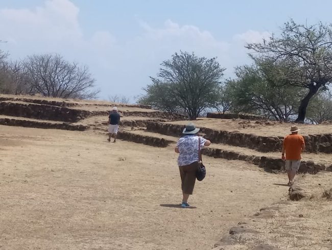 International tourists walking around Guachimontones archaeological site on a sunny day.