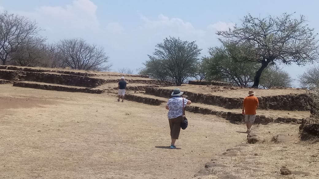 International tourists walking around Guachimontones archaeological site on a sunny day.