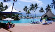 Beachfront swimming pool with restaurant and international tourists and residents enjoying the warm sunny days of Puerto Vallarta by the beach.