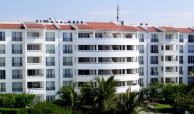 White Flamingos Beach and Golf condo building with red tiled roof, green areas on a clear sunny day.