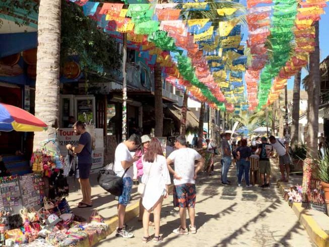 international tourists walking around Sayulita on the cobbledstoned streets with colorful markets.
